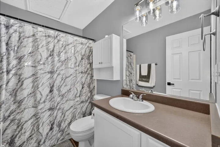 Bathroom featuring a single vanity with an integrated sink, broad countertop, and under-sink cabinetry