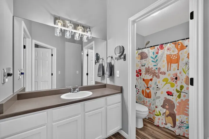 Bathroom featuring a vanity with white cabinetry, integrated sink, and a spacious countertop