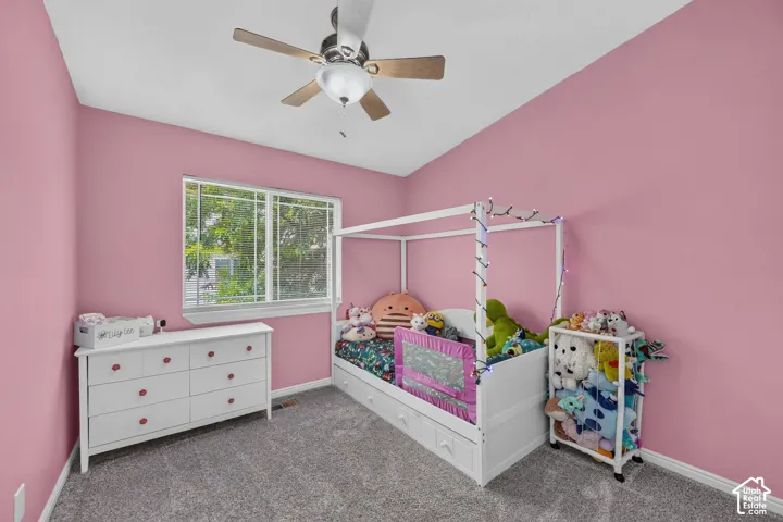 Room featuring a window with exterior views, a ceiling fan with integrated lighting, and neutral-toned carpeting