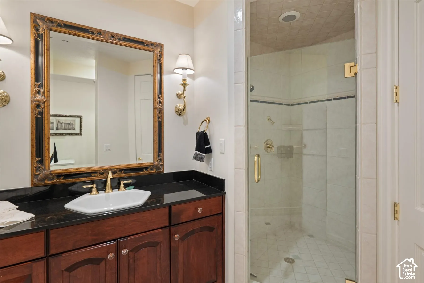 Bathroom featuring a dark wood-finish vanity with an octagonal vessel sink, gold-tone hardware, and a black countertop