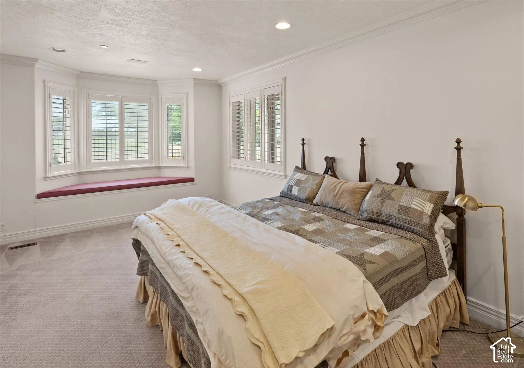 Bay window with a built-in window seat, plantation shutters, recessed lighting, and crown molding