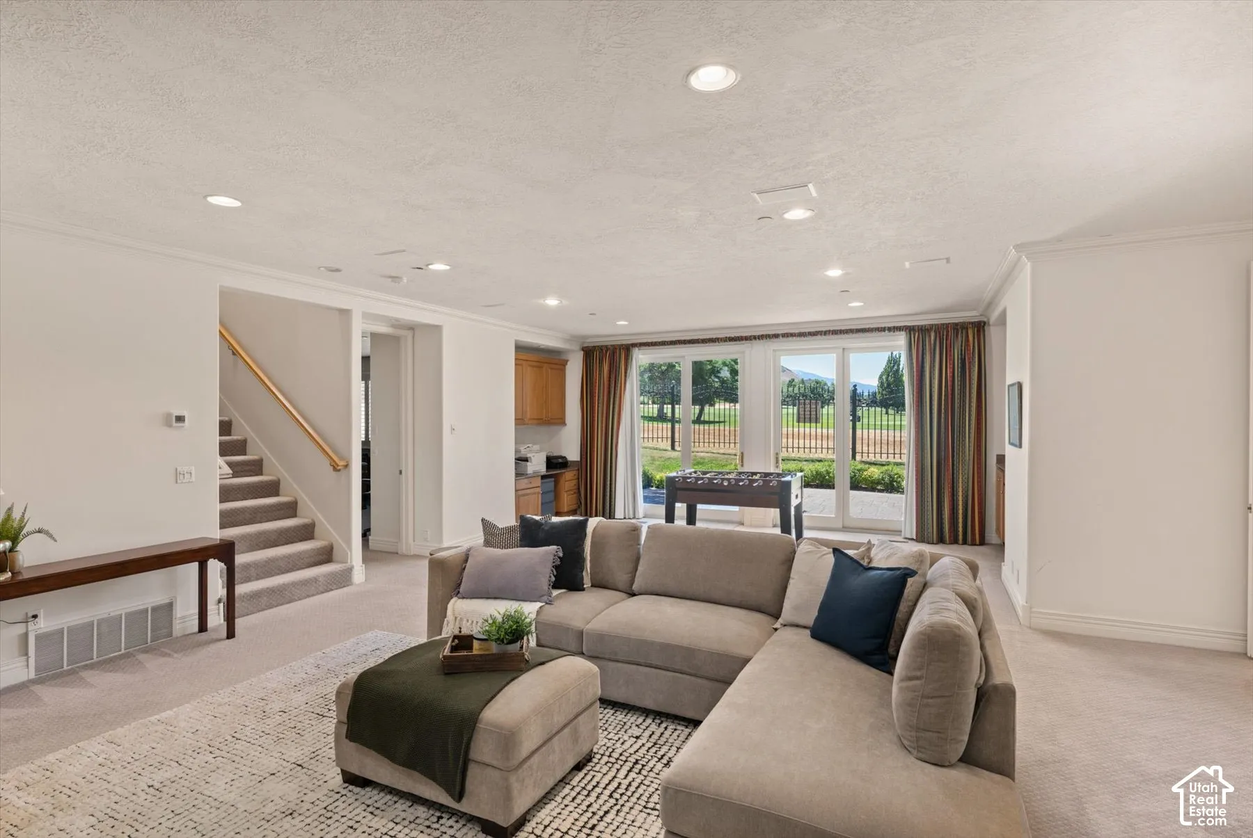 Spacious lower level featuring large sliding glass doors, recessed lighting, carpeted flooring, a built-in wet bar with wood cabinetry, and a carpeted stairway with a wood handrail