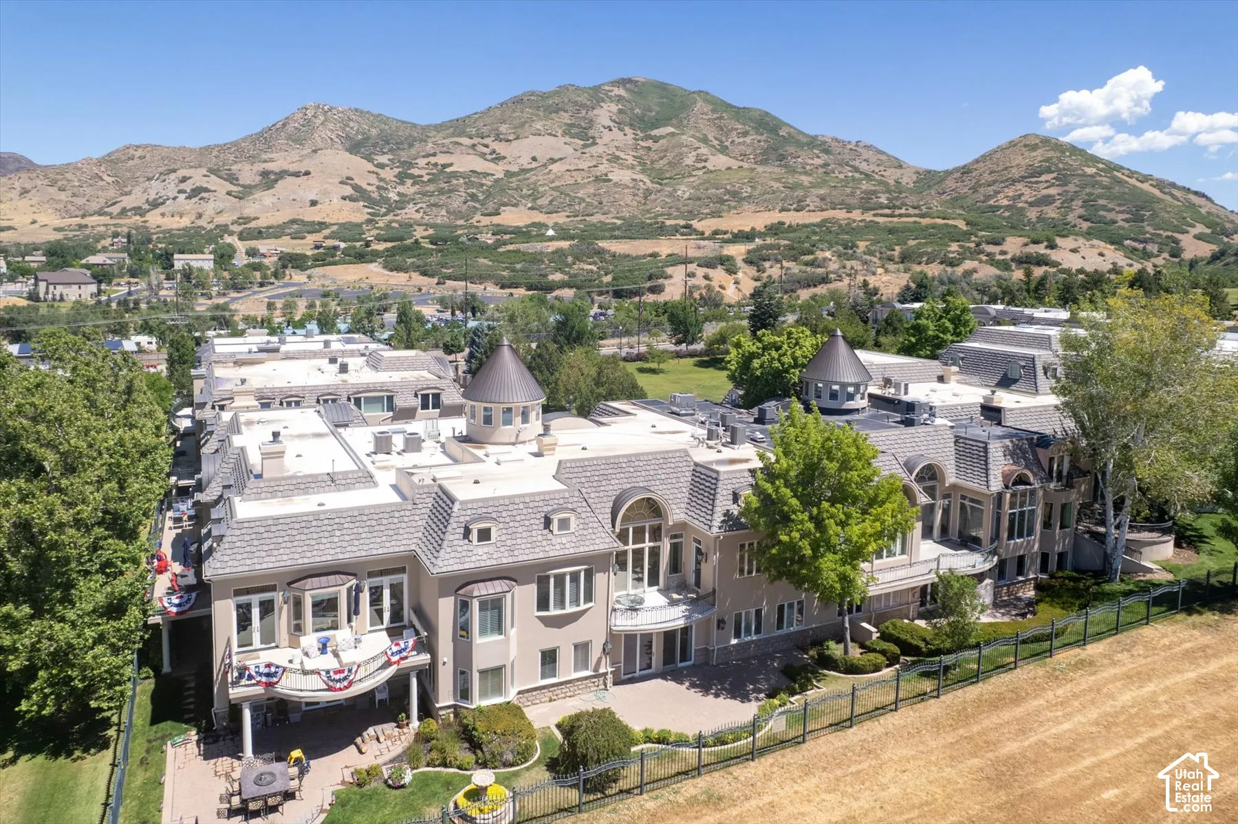 Expansive estate featuring multiple turrets, a multi-story balcony, and an outdoor patio with built-in planters