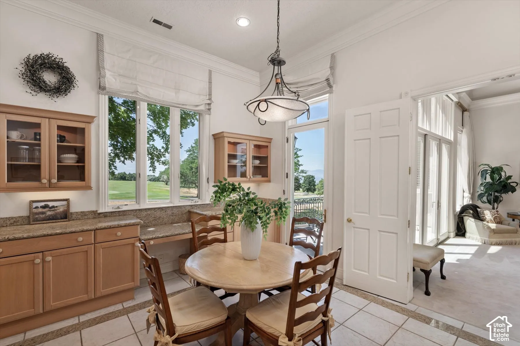 Dining area with large windows, light wood cabinetry, granite countertops, and tile flooring