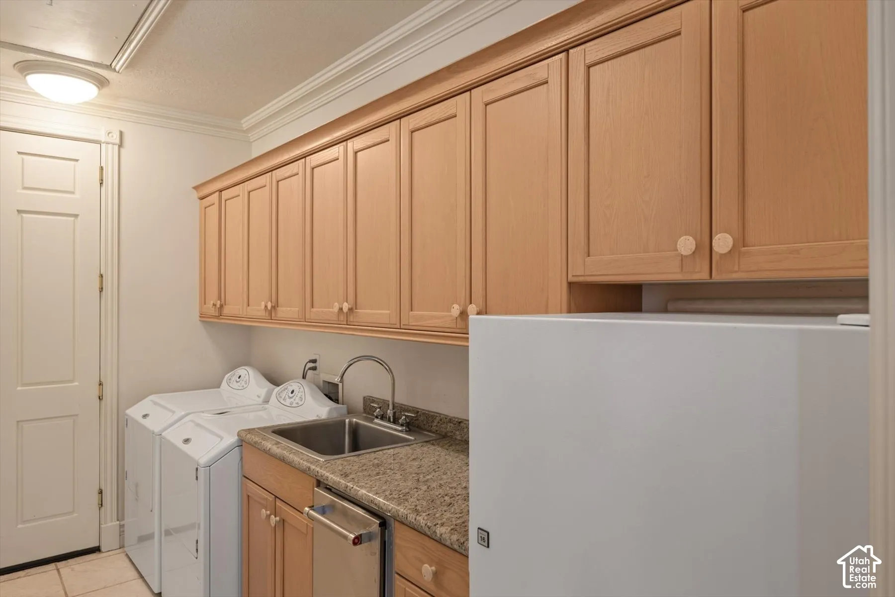 Laundry area with overhead wood cabinetry, granite countertop, and stainless-steel sink with a high-arc faucet, and extra refrigerator off kitchen