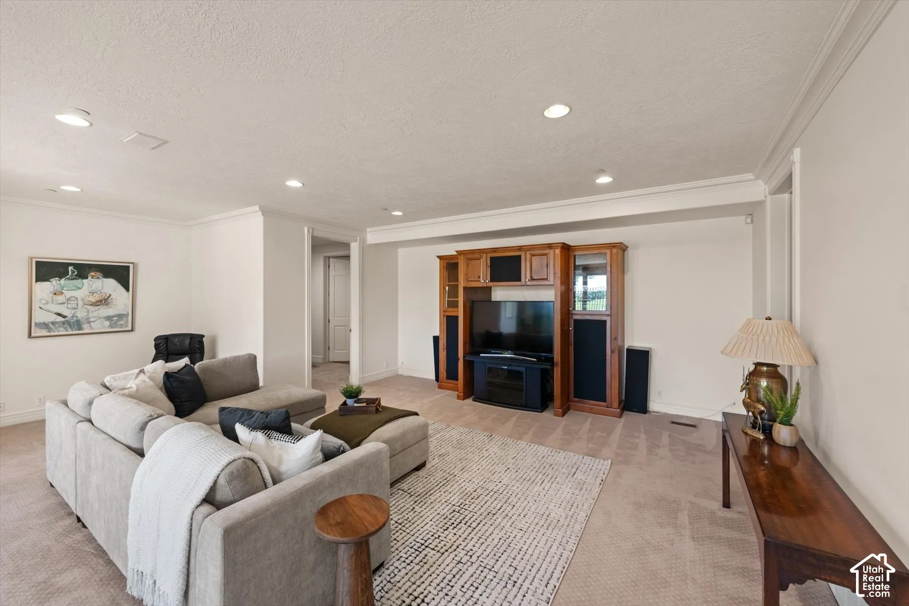 Spacious living area featuring recessed lighting, crown molding, light-colored carpeting, an entertainment center, and a neutral wall color