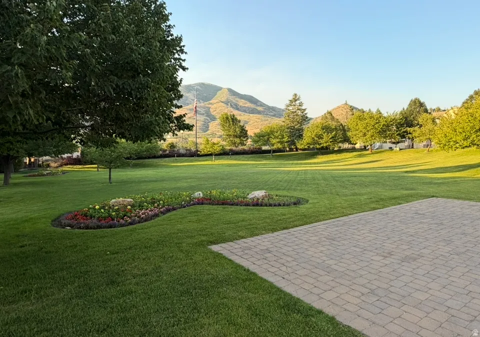 Expansive paver patio overlooking a manicured lawn with a decorative flower bed