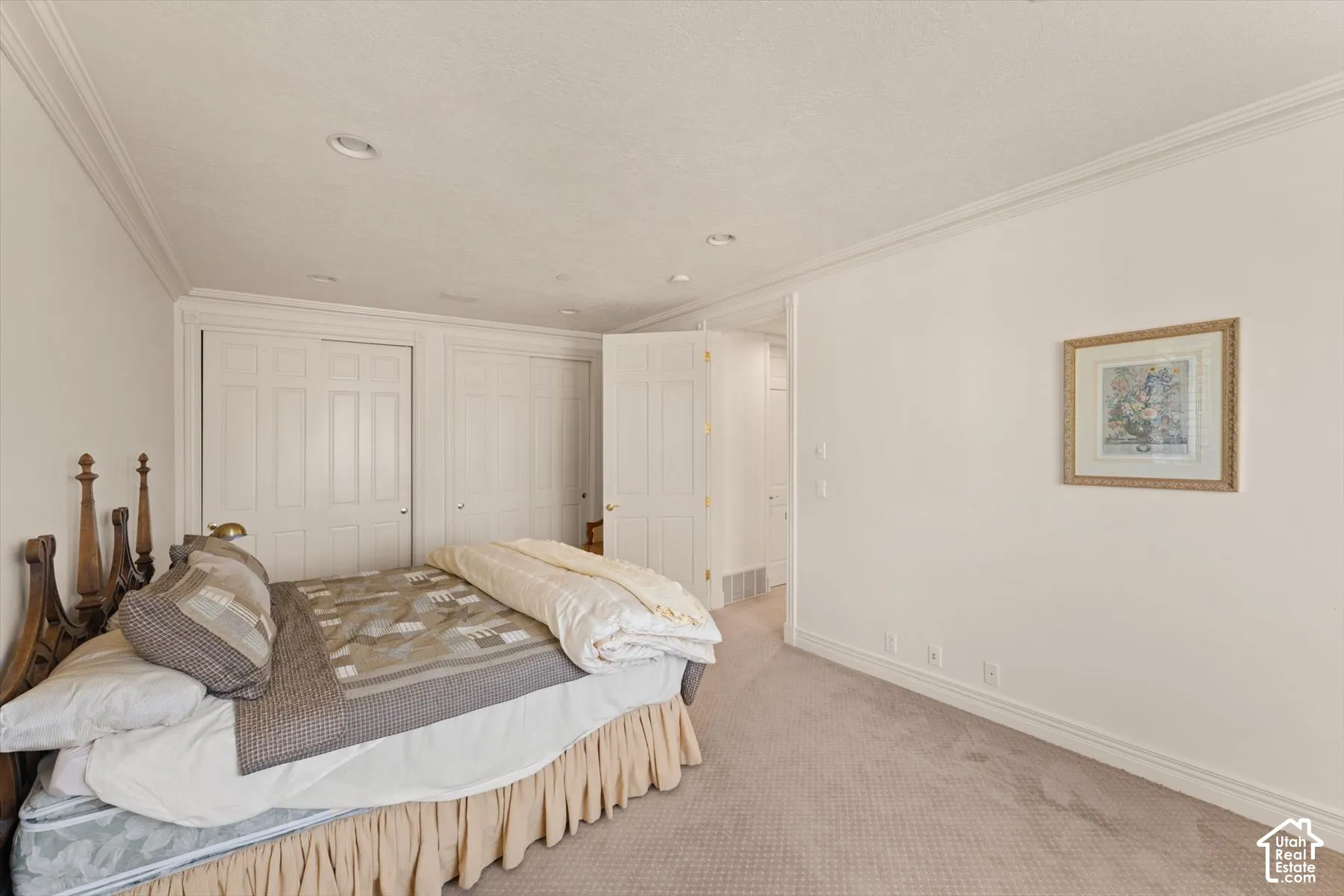 Carpeted bedroom featuring white walls, crown molding, recessed lighting, and white bi-fold closet doors