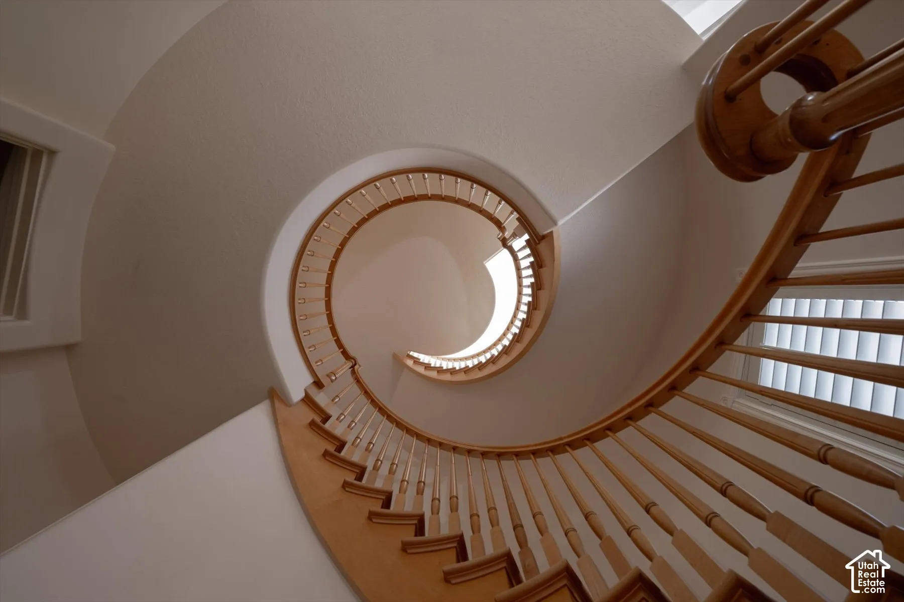 Spiral staircase featuring natural wood handrail and balusters
