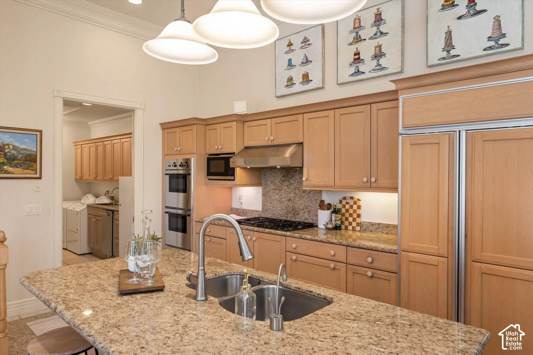 Gourmet kitchen featuring a large island with an undermount sink, granite countertops, wood cabinetry, stainless steel appliances, and high ceilings