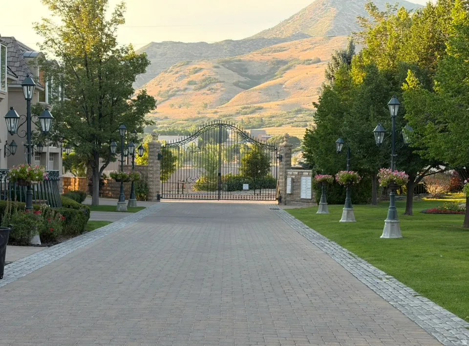 Paver driveway with cobblestone border, flanked by mature trees and manicured lawns