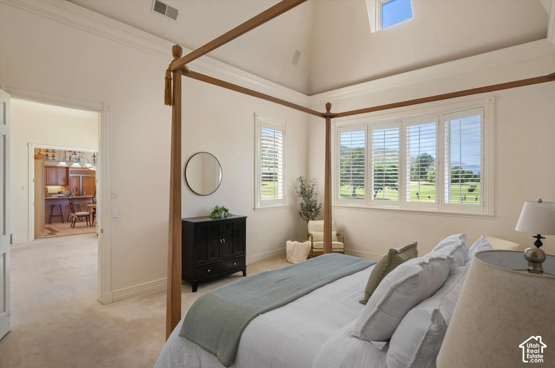 Spacious room featuring vaulted ceilings, a large window array with plantation shutters, and plush carpet flooring