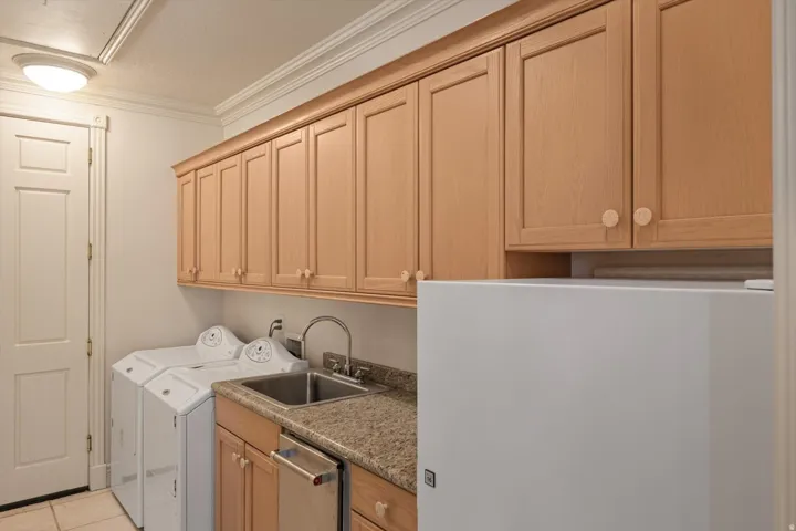 Laundry area with overhead wood cabinetry, granite countertop, and stainless-steel sink with a high-arc faucet, and extra refrigerator off kitchen