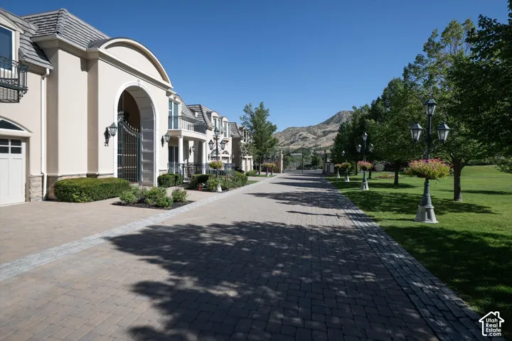Paved driveway bordered by mature trees and manicured lawn