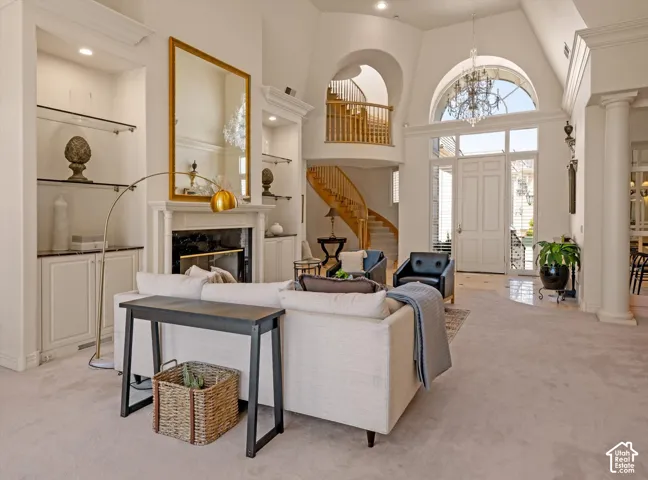 Spacious living area featuring a fireplace with a white mantel, built-in shelving with glass inserts, and high ceilings