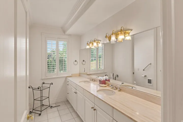 Expansive vanity with dual undermount sinks, a stone countertop and a shower