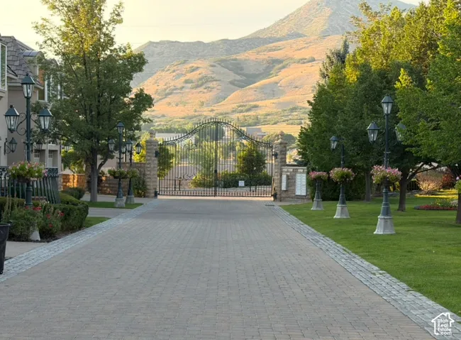 Paver driveway with cobblestone border, flanked by mature trees and manicured lawns