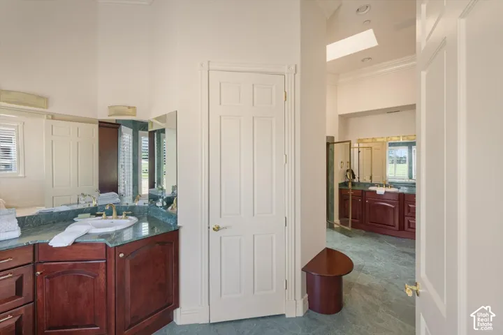 Spacious bathroom featuring two distinct vanity areas, each with a single sink and a green stone countertop