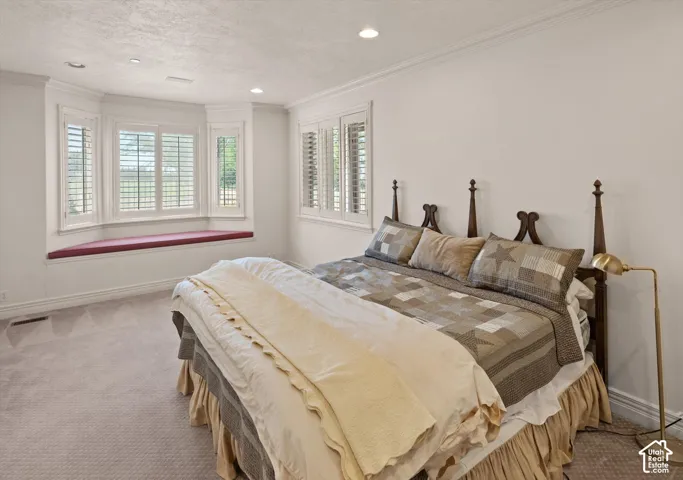 Bay window with a built-in window seat, plantation shutters, recessed lighting, and crown molding
