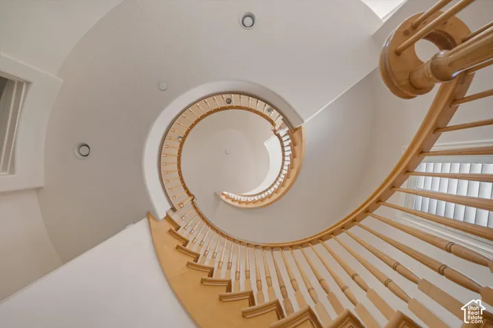 Curved staircase featuring natural wood balusters and handrail, recessed lighting, and  natural illumination