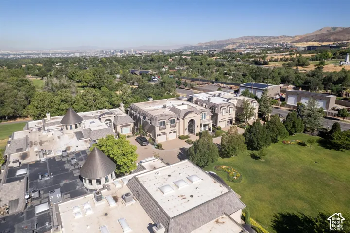 Expansive estate featuring multiple structures with arched entryways, extensive green spaces, and a mountainous backdrop