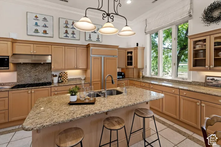 Spacious kitchen featuring an expansive central island with an integrated sink, cabinetry, granite countertops, and a full-height window overlooking exterior grounds