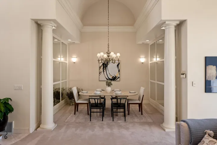 Formal dining area featuring architectural columns, an arched ceiling, recessed lighting, wall sconces, and a chandelier