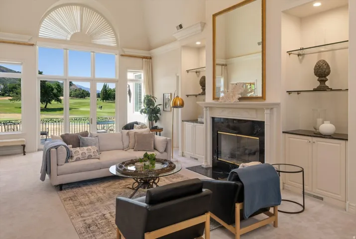 Vaulted ceiling living area featuring a prominent arched window, fireplace, built-in cabinetry with dark countertops, and integrated glass shelving