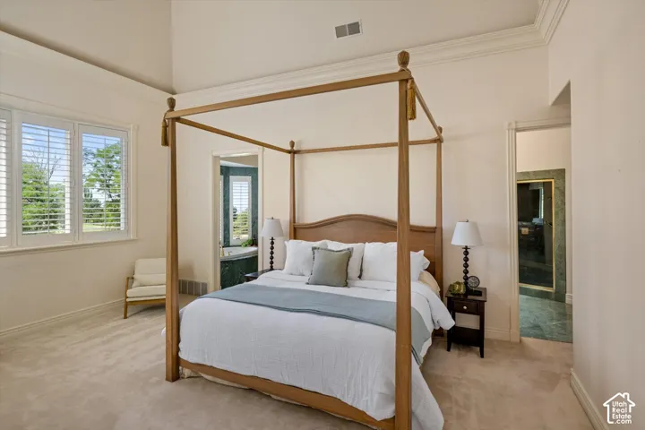 Carpeted bedroom featuring an arched doorway, vaulted ceiling, and crown molding