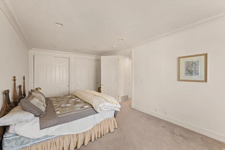 Carpeted bedroom featuring white walls, crown molding, recessed lighting, and white bi-fold closet doors