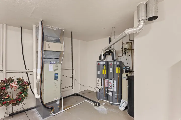 Utility area featuring a forced air furnace, two water heaters, and a water softener system