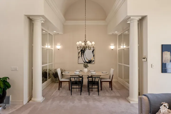 Formal dining area featuring architectural columns, an arched ceiling, recessed lighting, wall sconces, and a chandelier