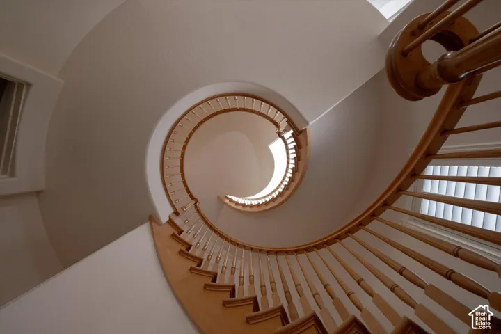 Spiral staircase featuring natural wood handrail and balusters