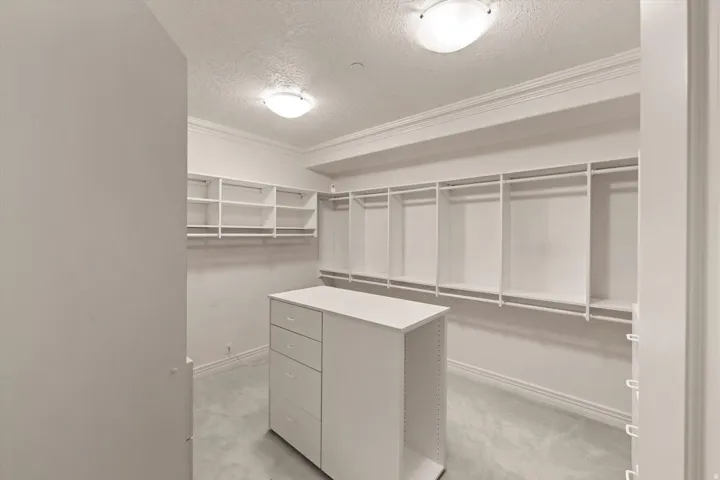 Customizable closet system with a central dresser island featuring multiple drawers and open shelving