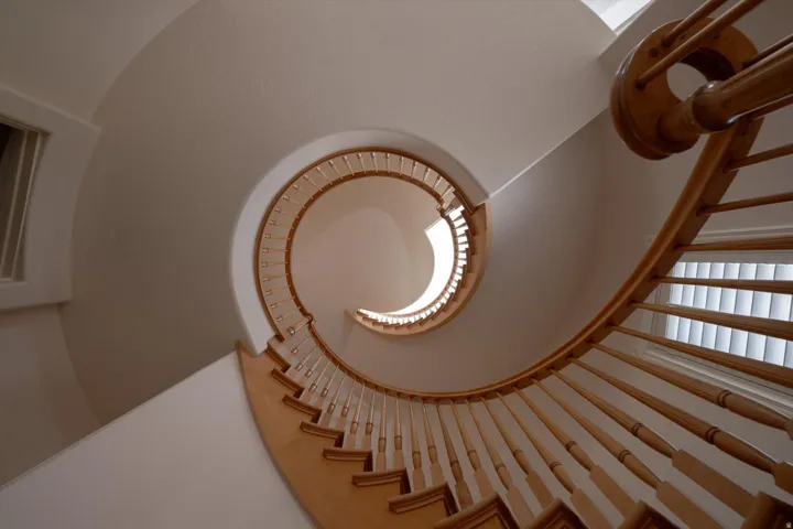 Spiral staircase featuring natural wood handrail and balusters