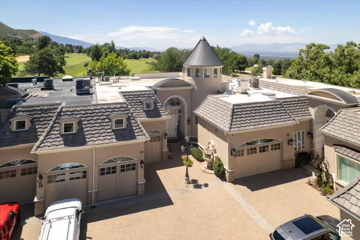 Expansive paver driveway leading to a multi-car garage with arched doors