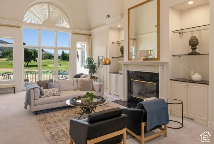 Vaulted ceiling living area featuring a prominent arched window, fireplace, built-in cabinetry with dark countertops, and integrated glass shelving