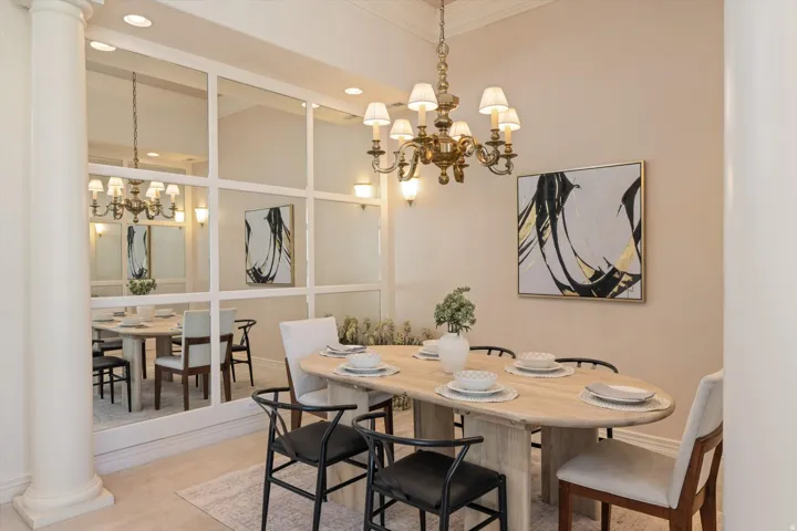 Formal dining area featuring a prominent mirrored wall, a classic brass chandelier, and a decorative wall sconce