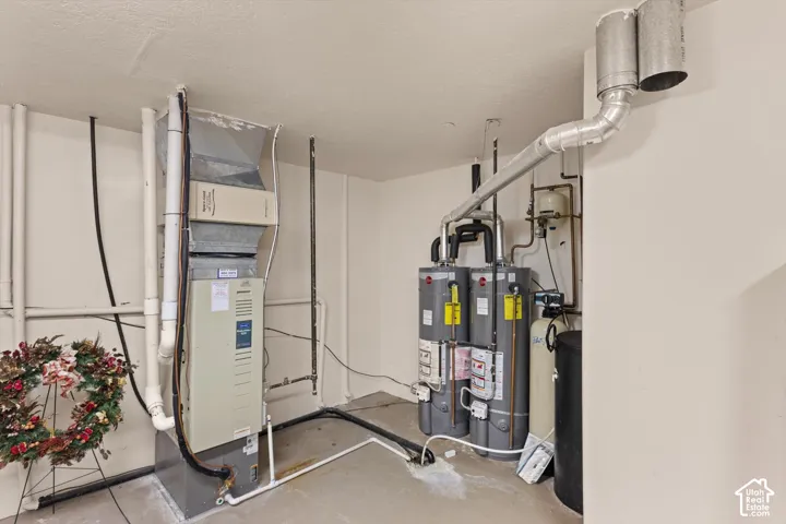 Utility area featuring a forced air furnace, two water heaters, and a water softener system