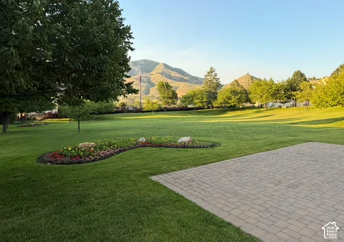 Expansive paver patio overlooking a manicured lawn with a decorative flower bed