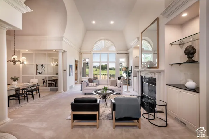 Spacious living area featuring vaulted ceilings, a large arched window, a fireplace with a stone mantel, built-in cabinetry with glass shelving, and light-toned carpeting