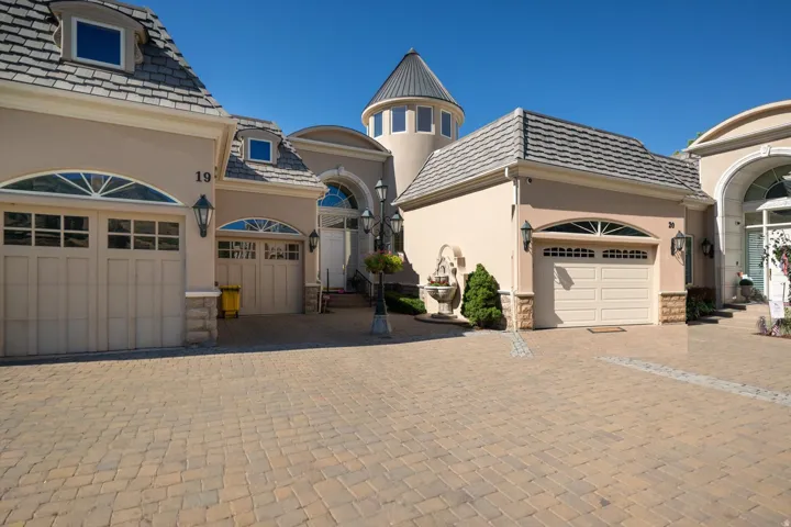 Stucco exterior with multiple garage bays, stone accents, and a distinctive turret feature