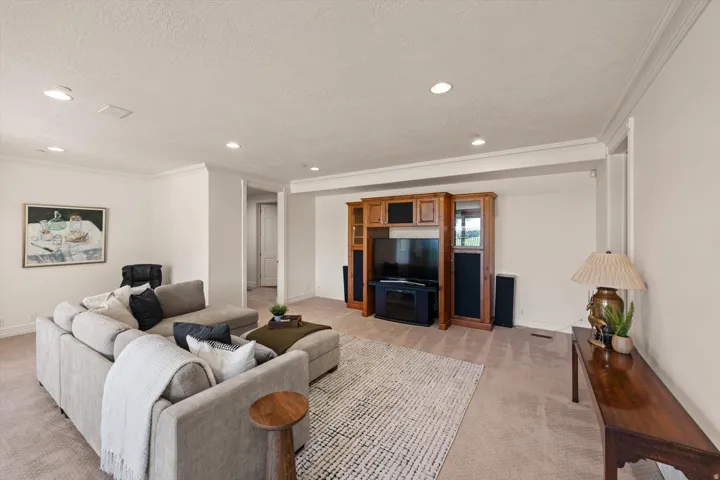 Spacious living area featuring recessed lighting, crown molding, light-colored carpeting, an entertainment center, and a neutral wall color