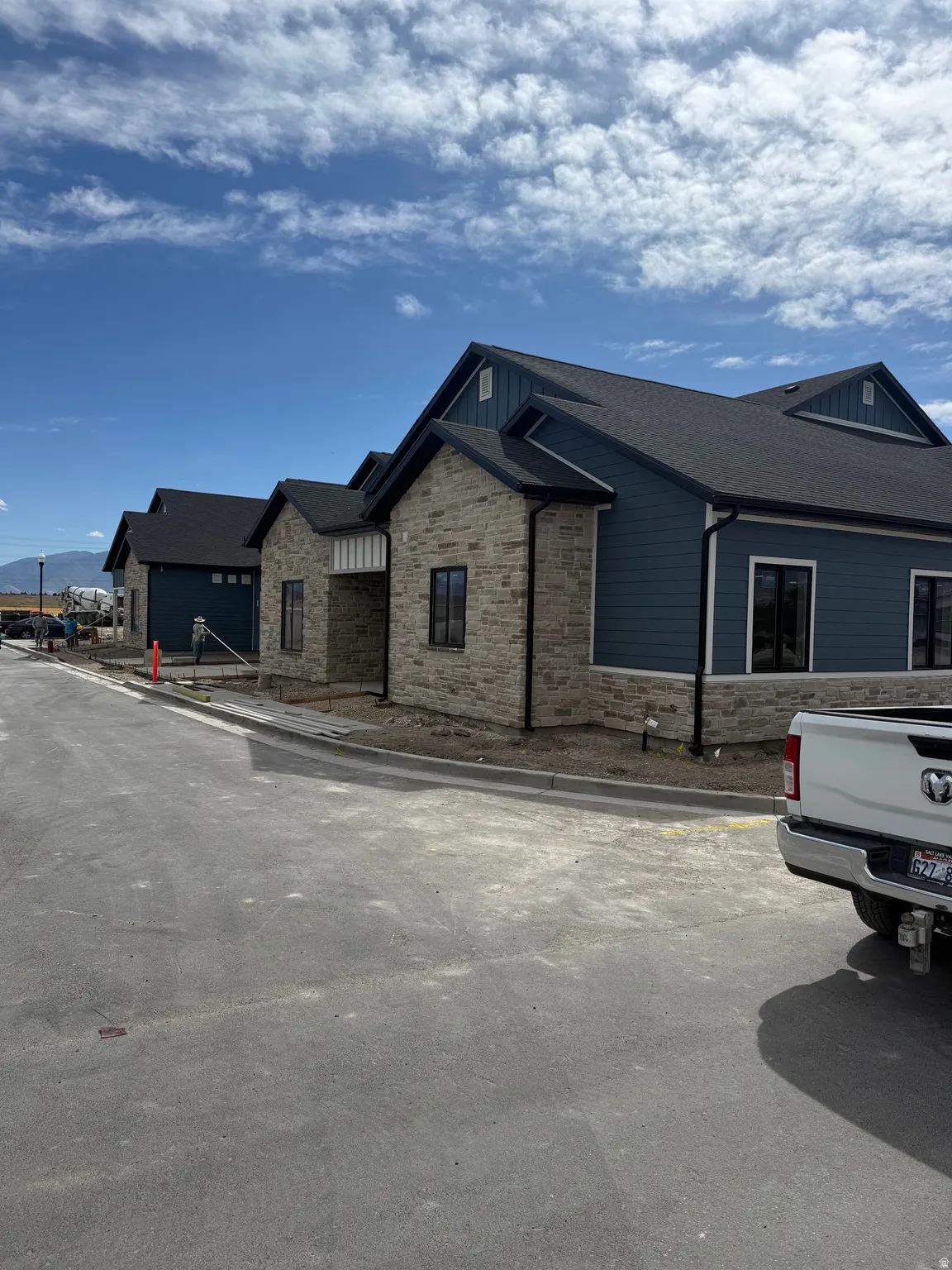 Newly constructed home featuring a dark shingle roof, blue siding, and stone façade detailing
