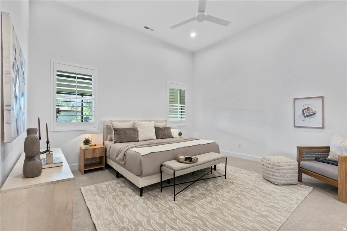 Spacious room featuring vaulted ceilings, light-tone carpeting, and two windows with white plantation shutters