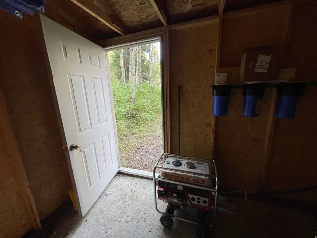 Utility space featuring wood-finish walls, a white paneled door, and a three-stage water filtration system