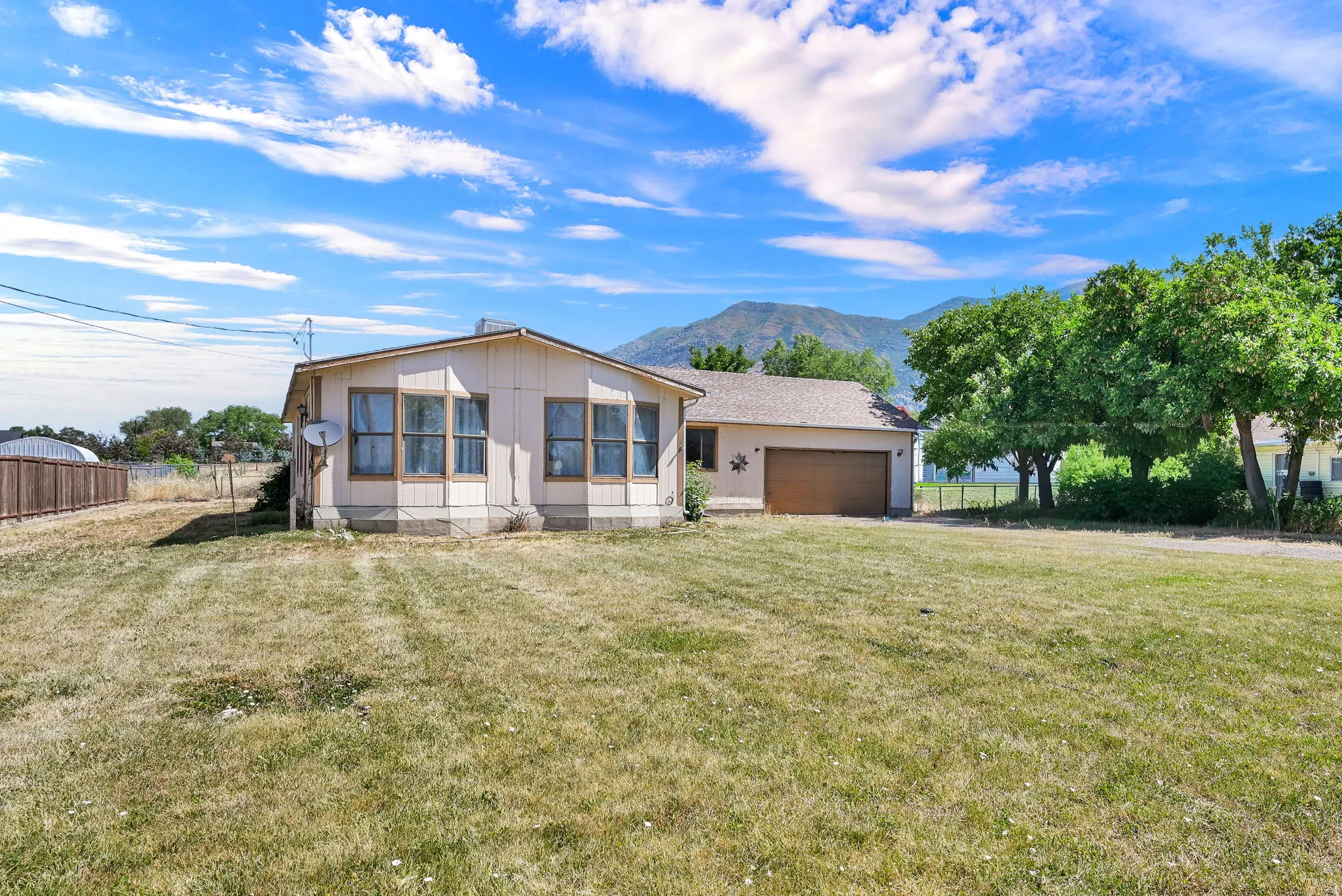 Single-story residence featuring a bay window, attached garage, and a spacious front yard