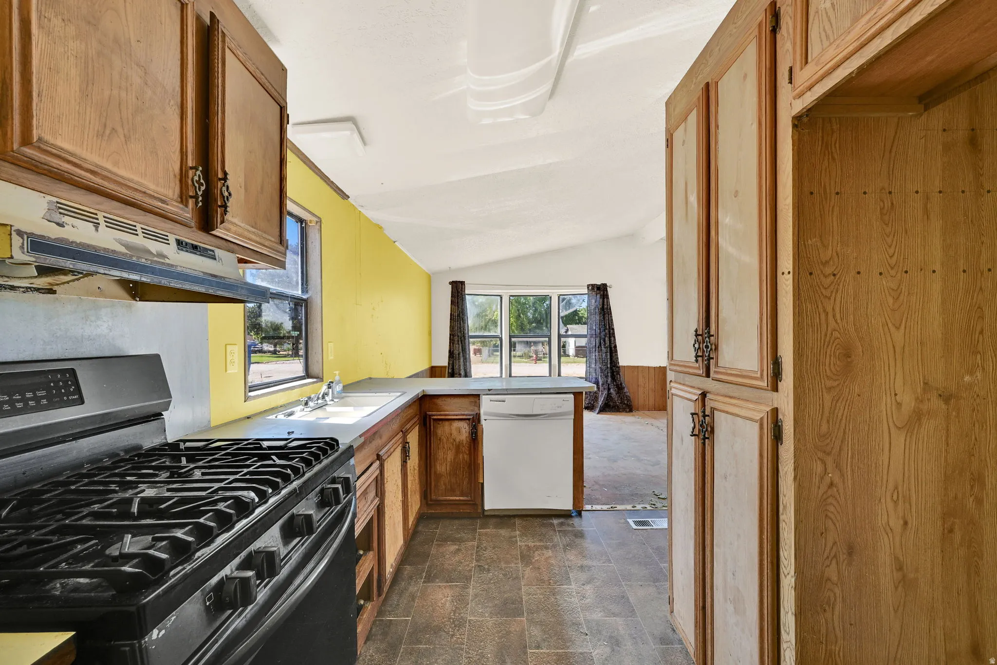 Kitchen featuring wood cabinetry, a built-in oven with a gas range, a white dishwasher, a stainless steel sink, and a window