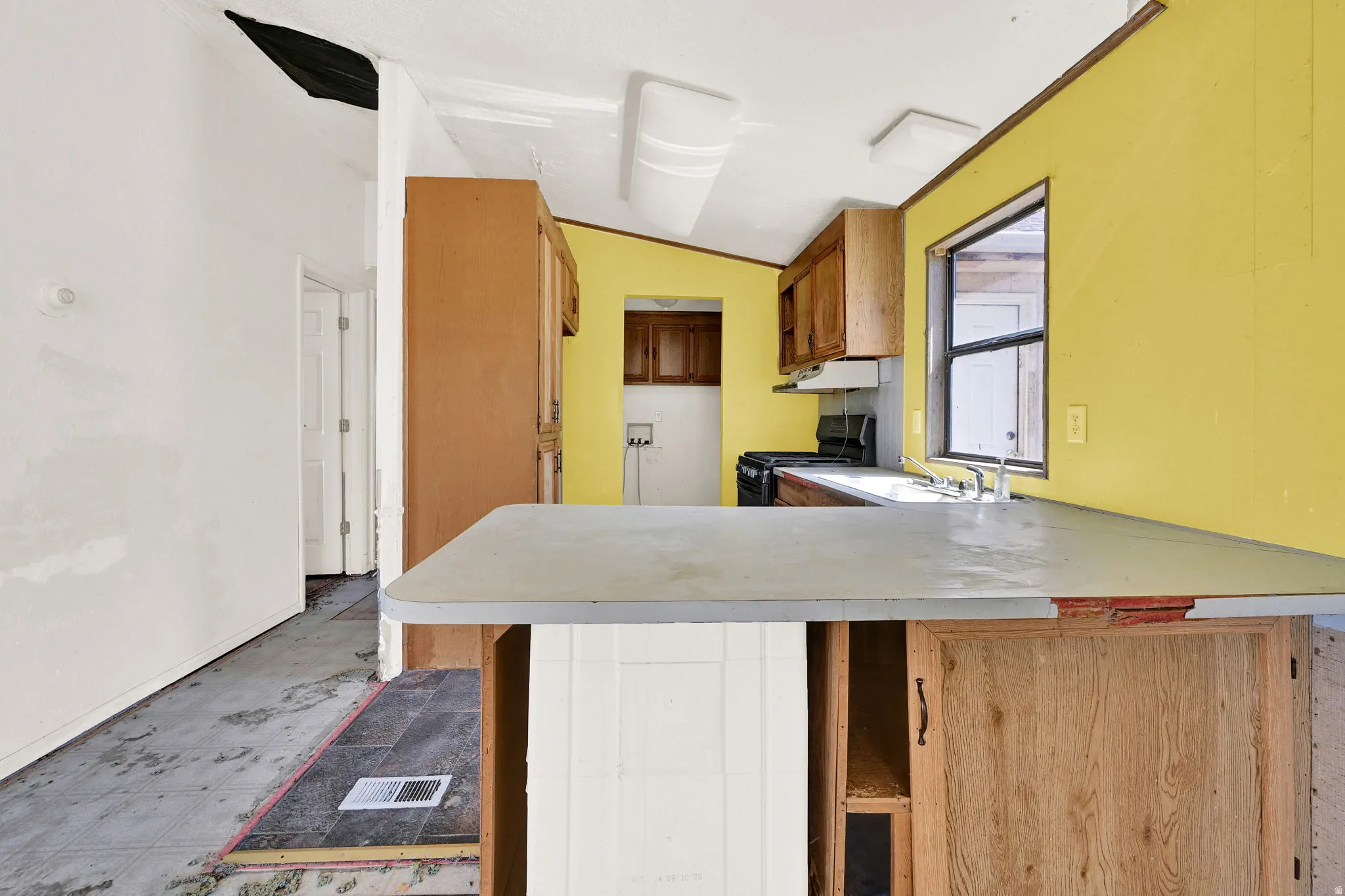 Kitchen area featuring a built-in peninsula, wood-finish cabinetry, a window, a stainless steel sink, and an electric range