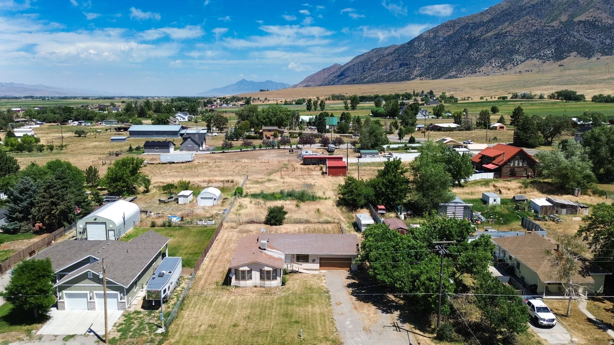 Single-story property featuring a tan exterior, an attached garage, a gravel driveway, and rural location